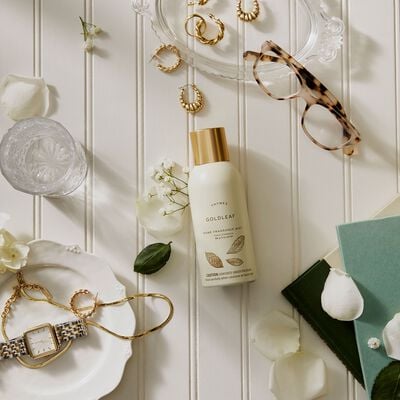 Thymes Goldleaf Home Fragrance Mist surrounded by flowers